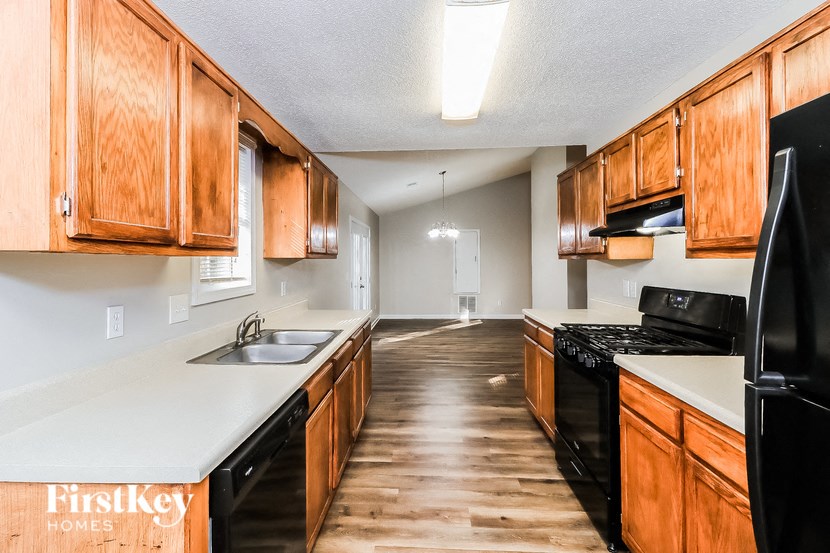 a kitchen with wood cabinets and black appliances and white counter tops