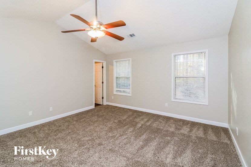 the spacious living room with carpet and ceiling fan