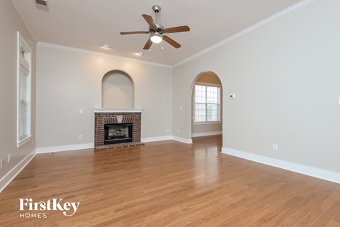 A spacious room with a fireplace and a ceiling fan.