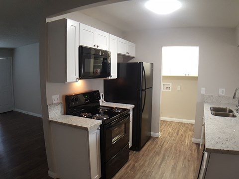 A kitchen with a black refrigerator and stove.