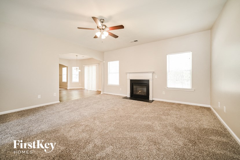 an empty living room with a fireplace and a ceiling fan