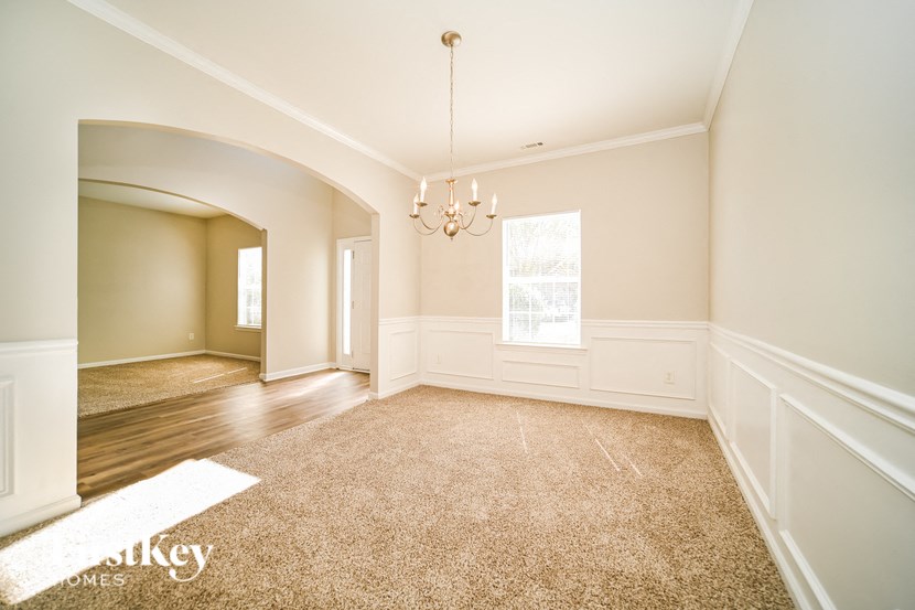an empty living room with a rug and a chandelier