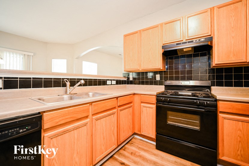 a kitchen with black appliances and wooden cabinets and black tile
