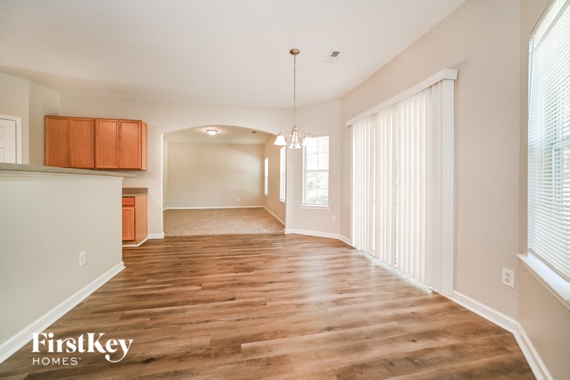 an empty living room and kitchen with wood flooring and large windows