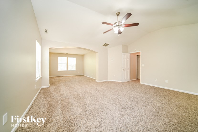 a spacious living room with carpet and a ceiling fan