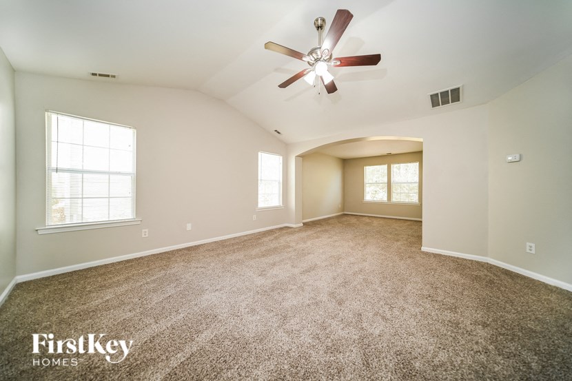 a spacious living room with carpet and a ceiling fan