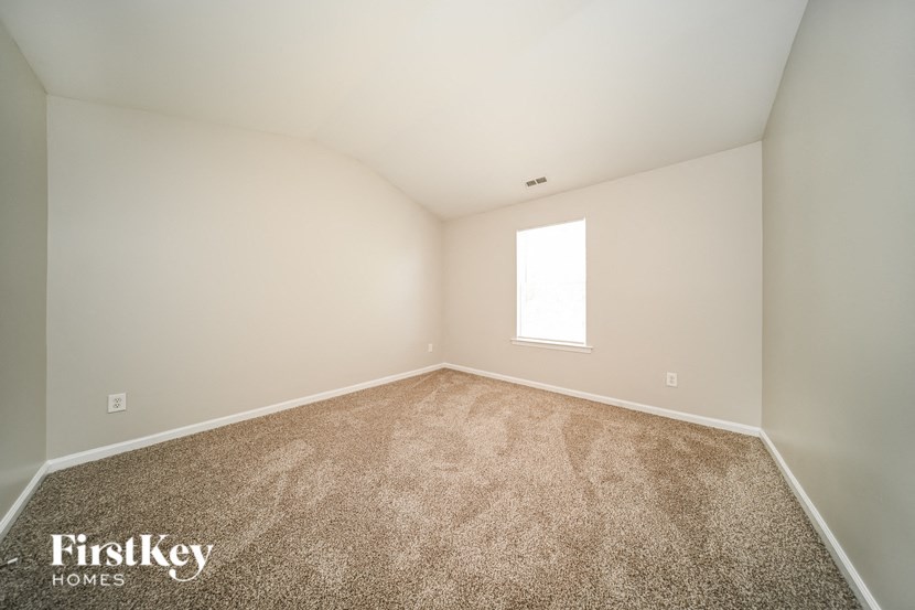 a spacious room with carpet and a window