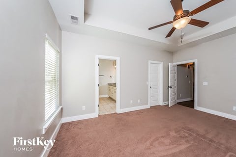 a living room with a ceiling fan and a carpet