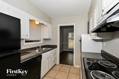 A kitchen with black appliances and white cabinets.