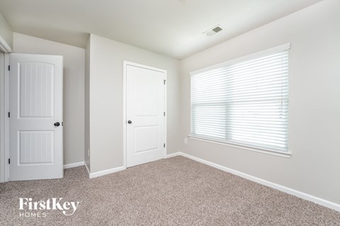 a bedroom with a door and a window and a carpeted floor