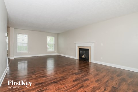 A spacious room with wooden floors and a fireplace.