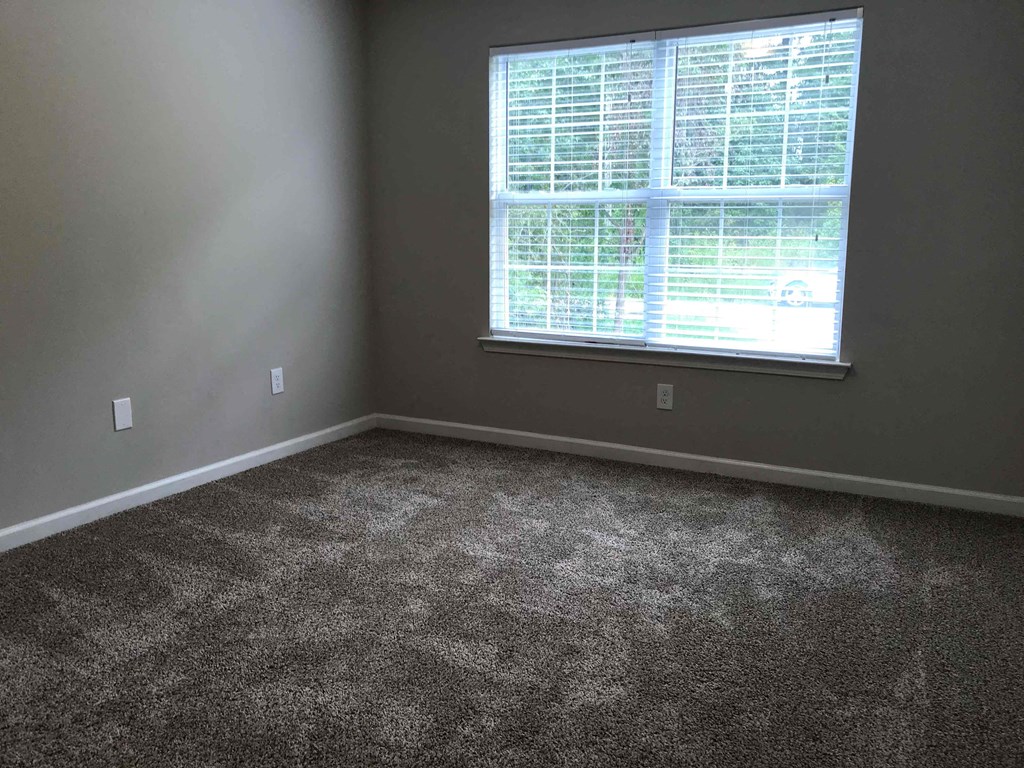 a room with a window and a carpeted floor