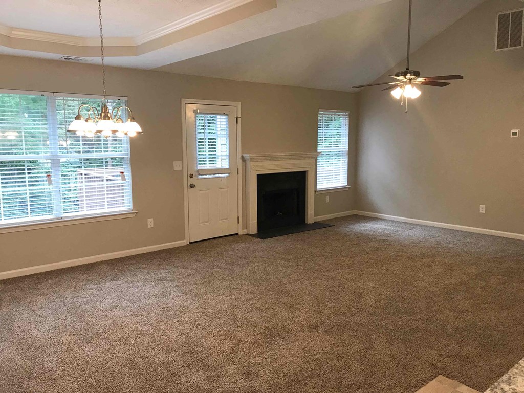 an empty living room with a fireplace and a ceiling fan