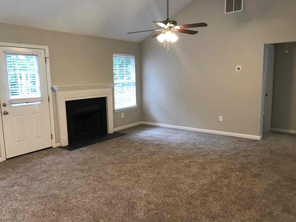 a living room with a fireplace and a ceiling fan