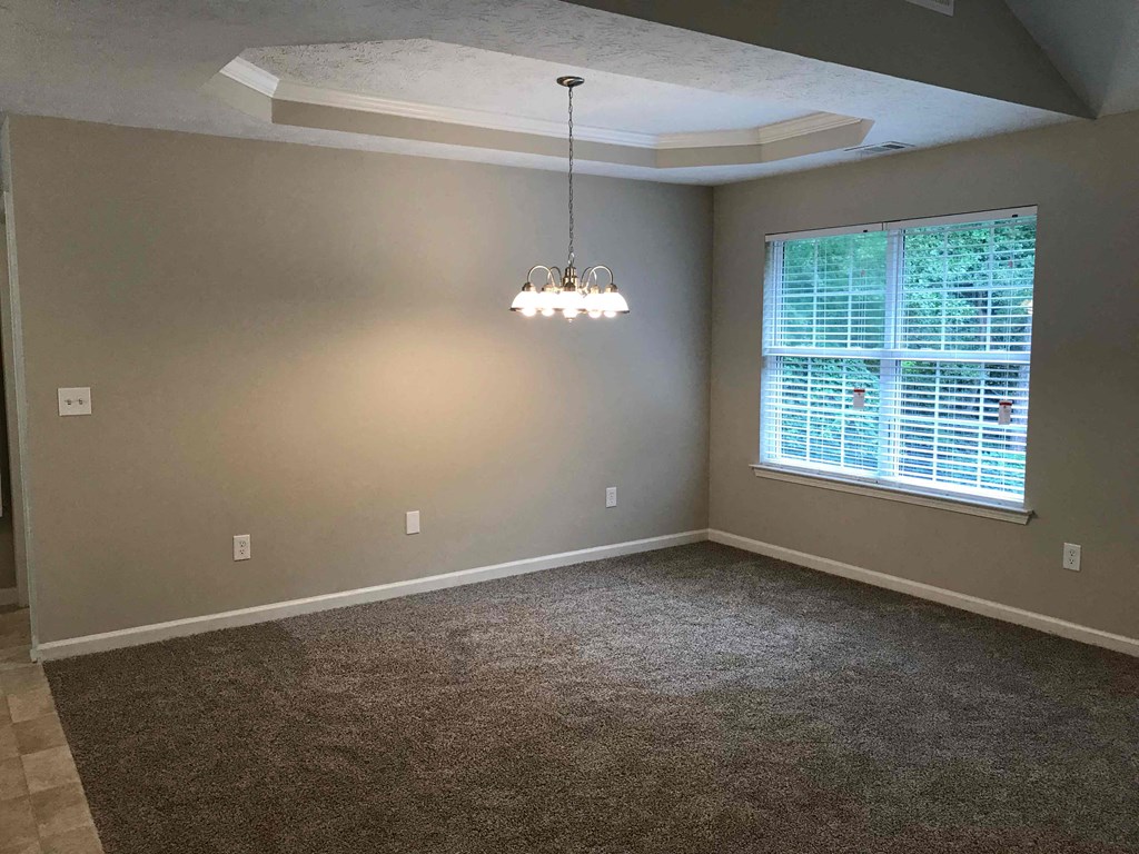 a empty living room with a window and a chandelier