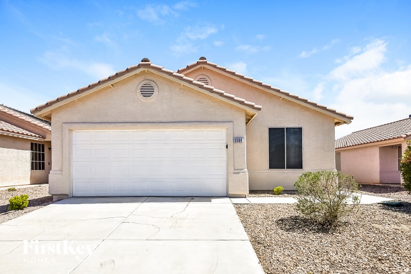 A beige house with a white garage door and a small window on the side.