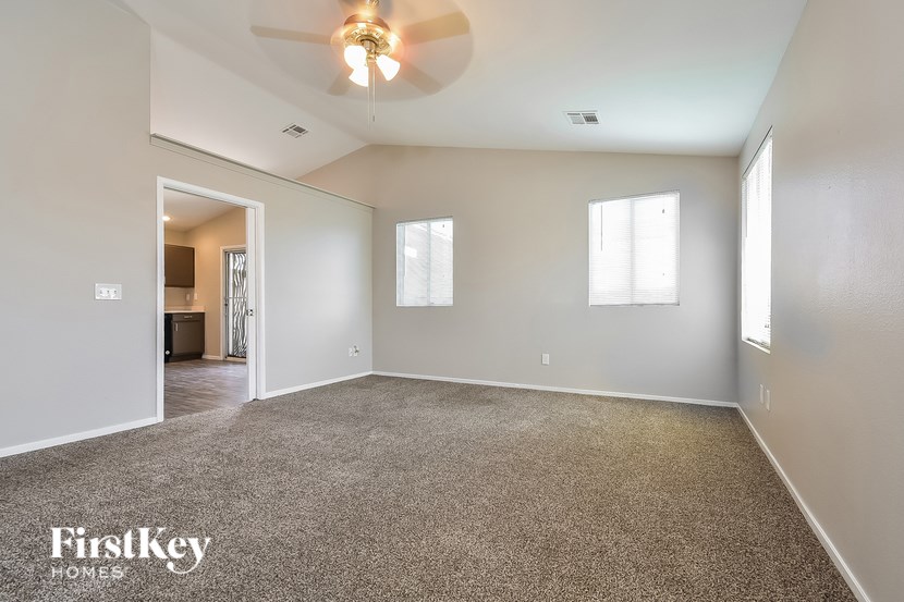 A spacious room with a carpeted floor and a ceiling fan.