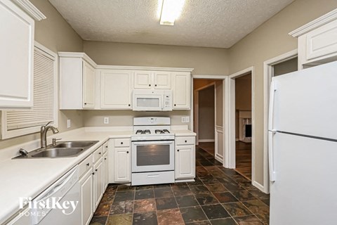 a kitchen with white cabinets and a sink and a refrigerator