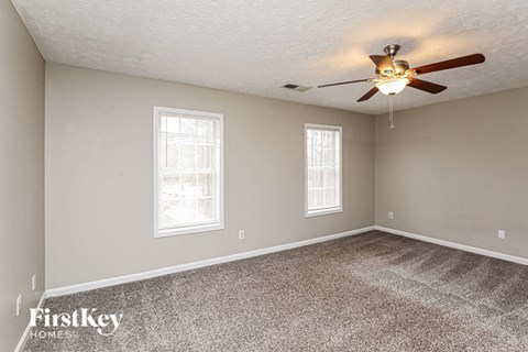 the spacious living room with ceiling fan and carpet