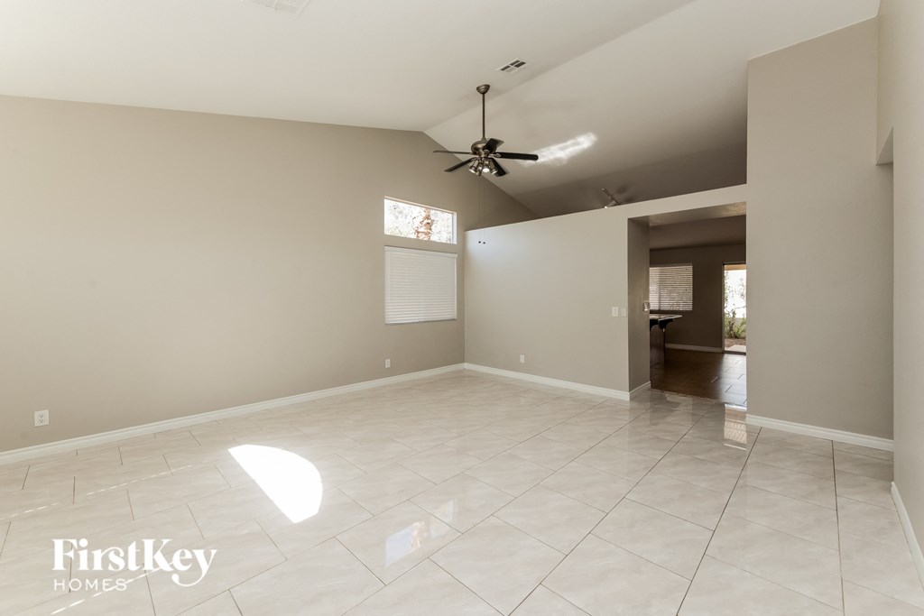 an empty living room with a ceiling fan and a tiled floor