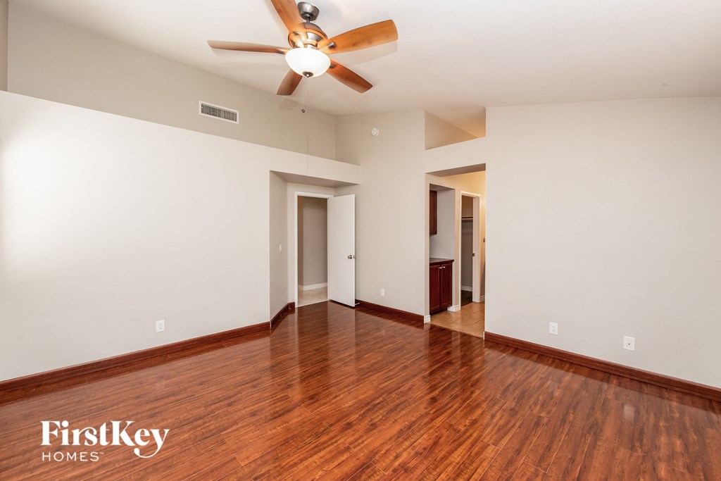an empty living room with wood floors and a ceiling fan