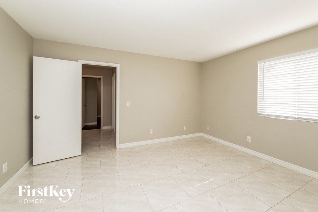 an empty room with a door to a hallway and a tiled floor