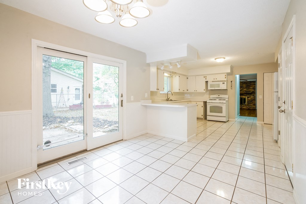 an open kitchen with a door to the backyard and a white tiled floor