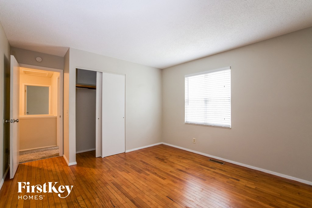 the living room of an empty house with wood floors and a window