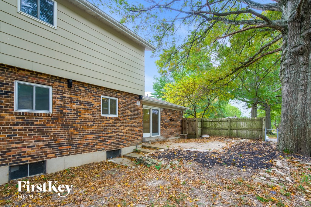 a backyard with a brick house and a tree