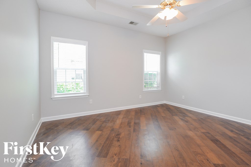 a clean and empty room with wood floors and a ceiling fan