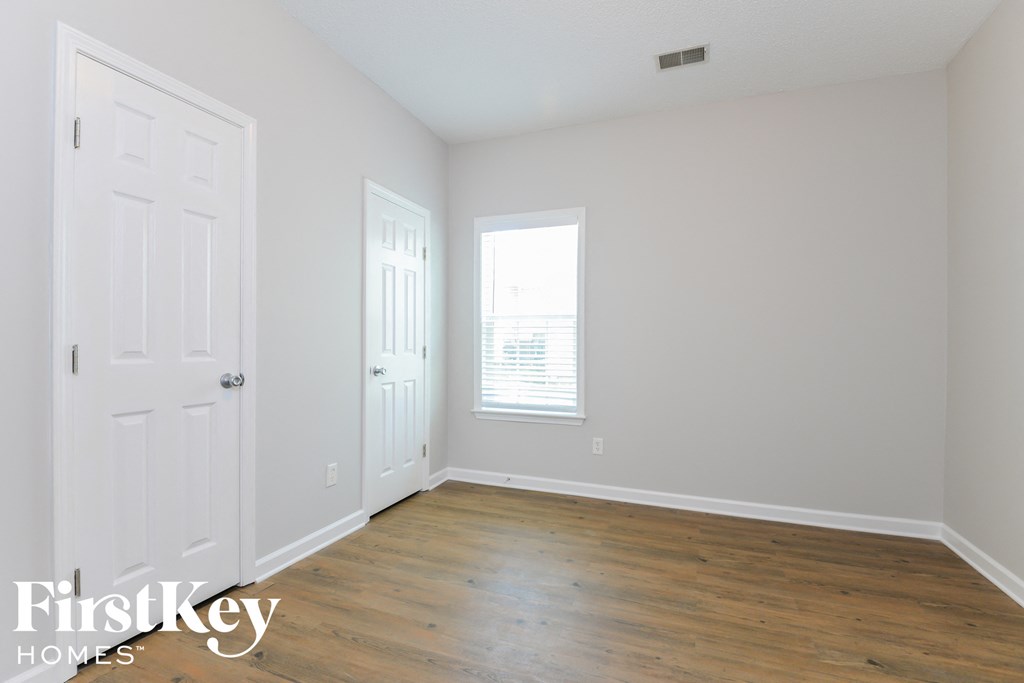 a bedroom with white walls and wood floors and a white door