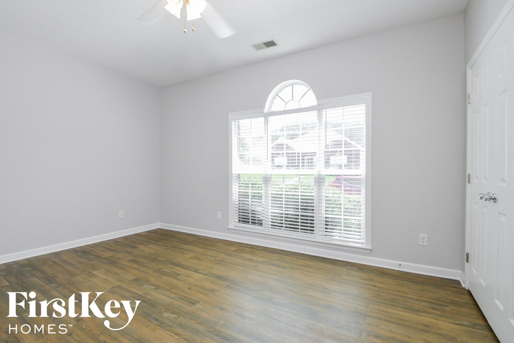 the second bedroom with wood floors and a large window