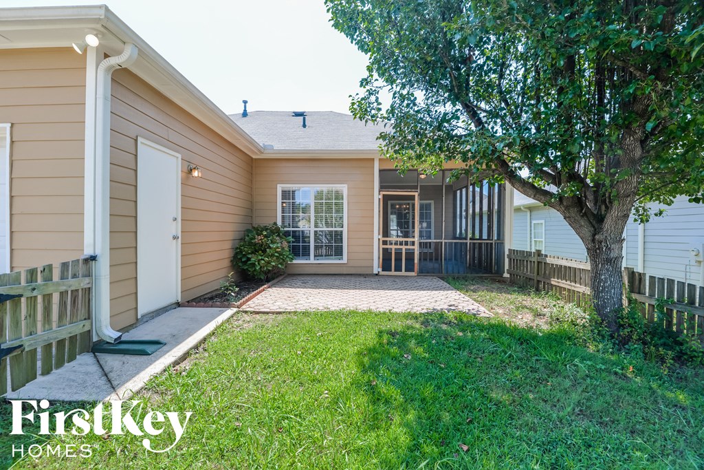 a small tan house with a yard and a tree