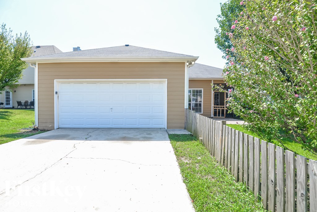 a white driveway in front of a house with a white fence