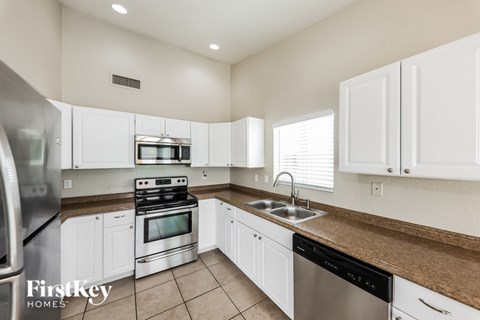 A kitchen with white cabinets and a stainless steel refrigerator.
