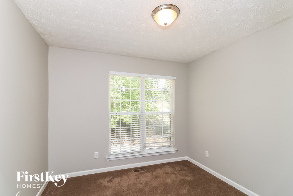 a bedroom with a large window and a carpet