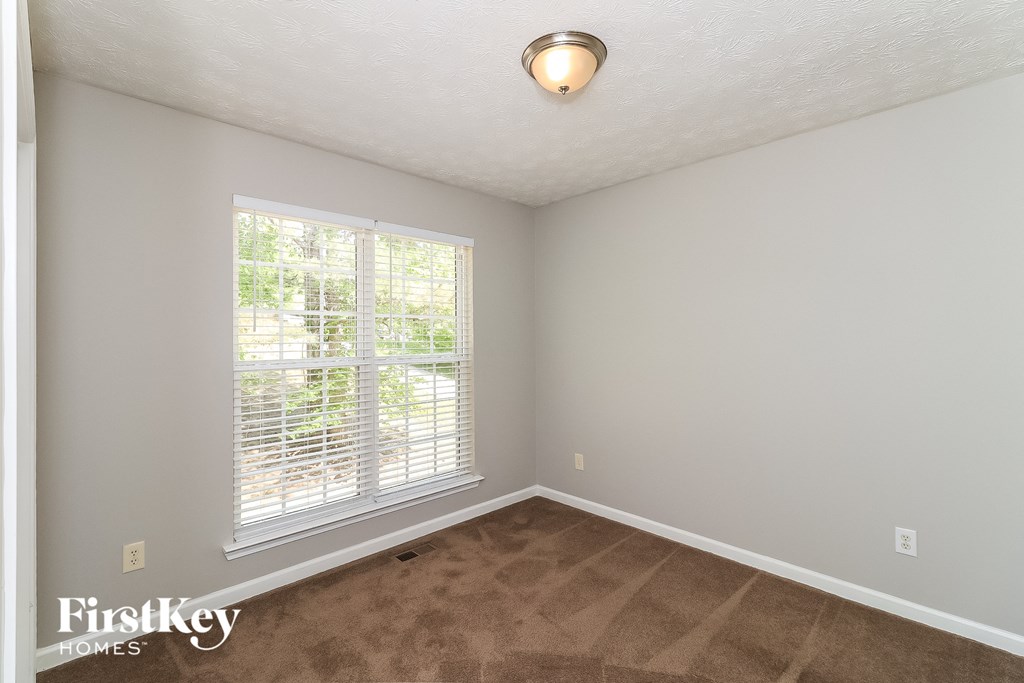 the living room of an empty home with a large window and carpeting