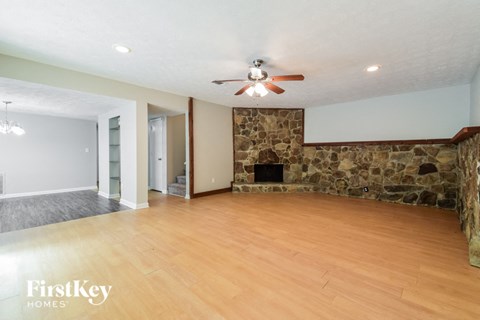 a living room with a stone fireplace and a ceiling fan
