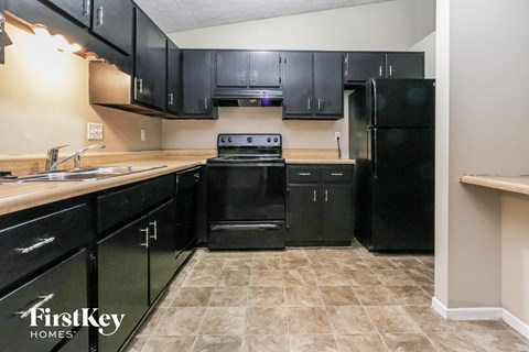 A kitchen with black cabinets and a black stove top oven.