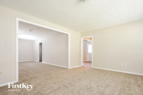 a spacious living room with carpet and white walls