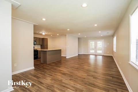 A spacious room with wooden flooring and a large window on the right side.