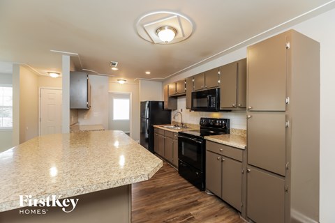 A kitchen with a granite countertop and wooden floors.