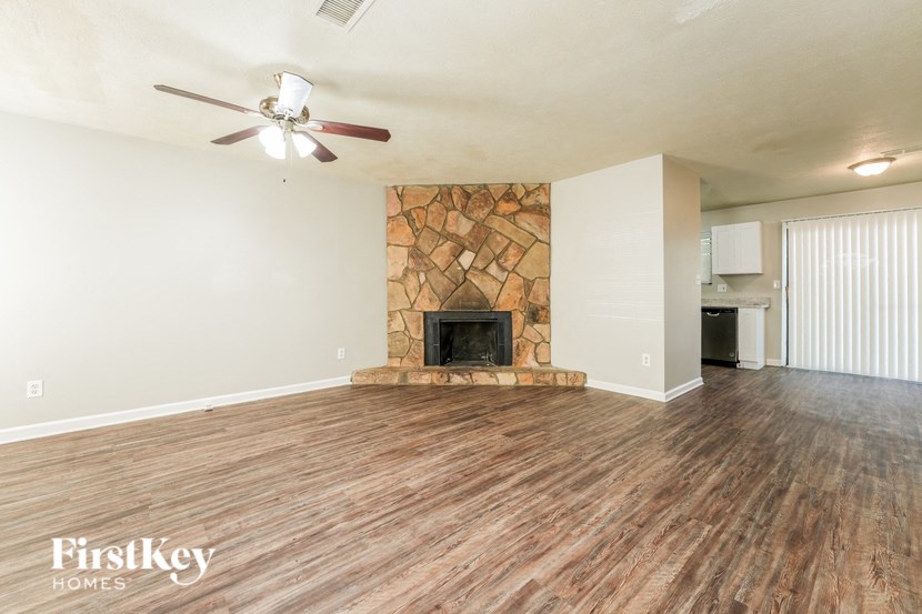 the living room with wood flooring and a stone fireplace