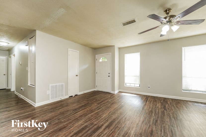 an empty living room with wood floors and a ceiling fan