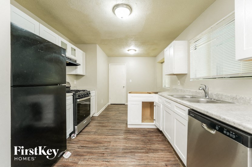 a kitchen with white cabinets and stainless steel appliances and a black refrigerator