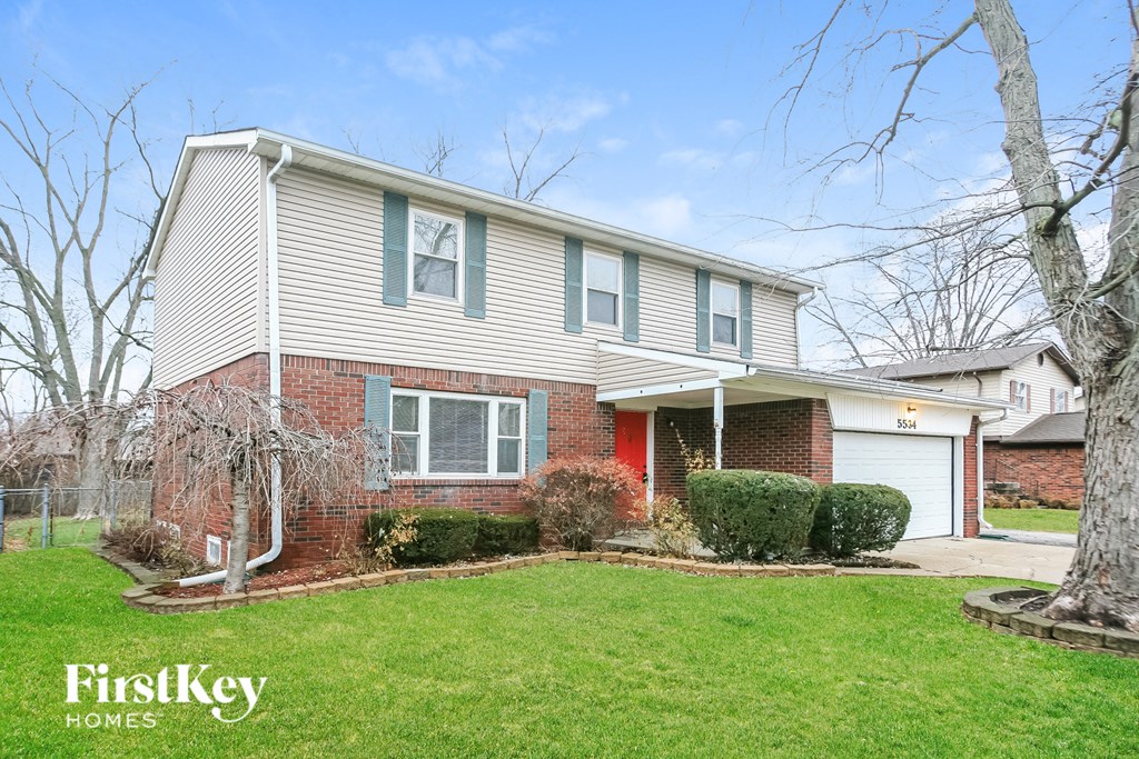 A house with a red door and a garage is for sale.