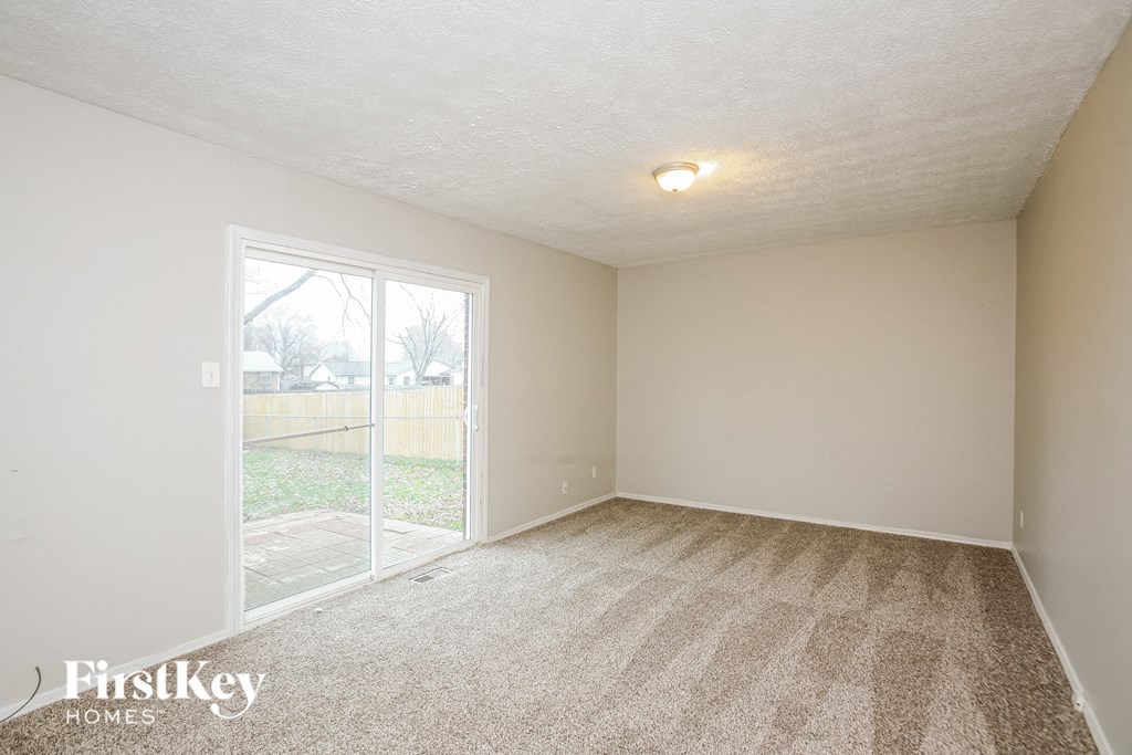 A room with a carpeted floor and a sliding glass door leading to a backyard.