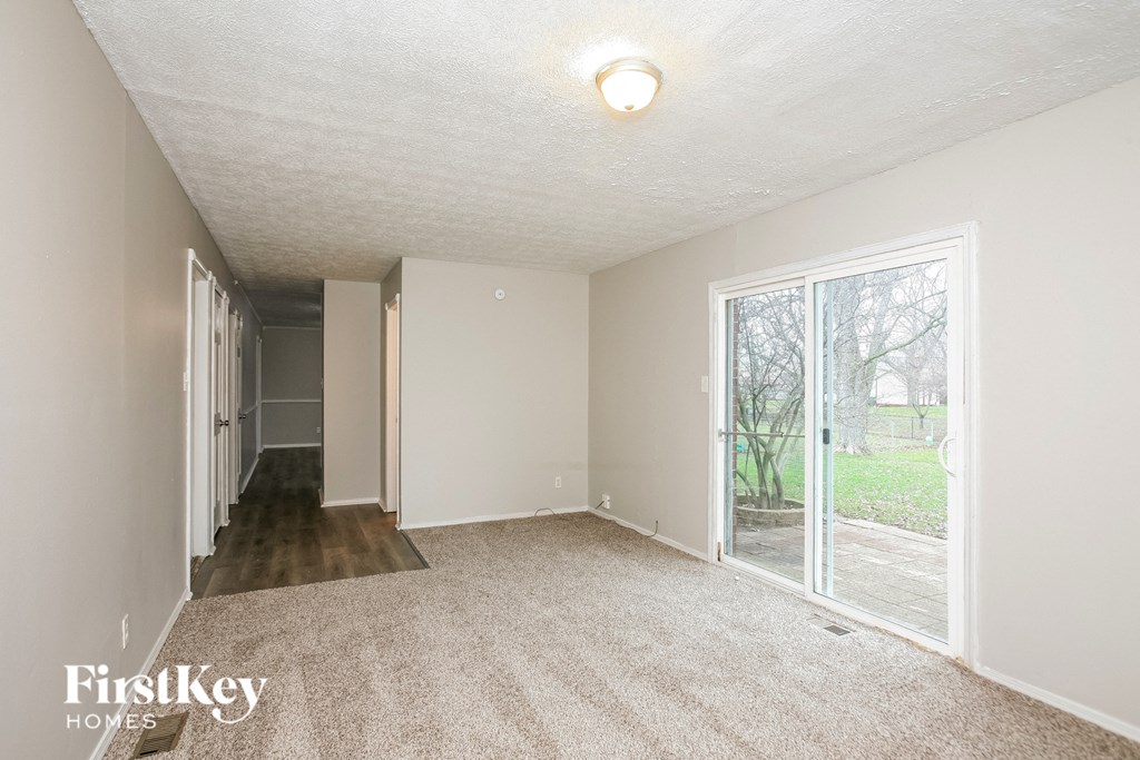 A room with a carpeted floor and a sliding glass door leading to a backyard.