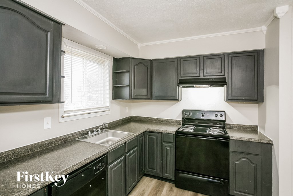 A kitchen with black cabinets and a black stove top oven.