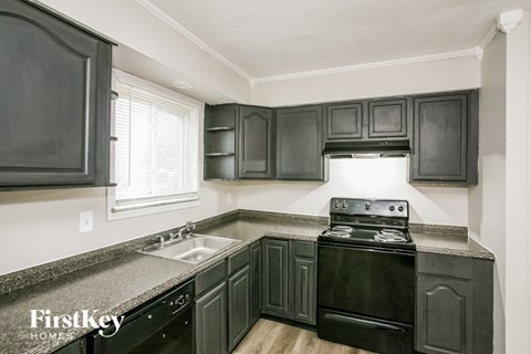 A kitchen with black cabinets and a black stove top oven.